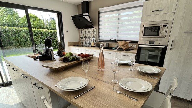 A modern kitchen with a wooden countertop, white cabinets, and a built-in oven. - DEGEMER MAT! Cosy, Modern, 8 minutes from the beach (Moëlan-sur-Mer)