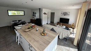 A modern kitchen with a large island, dining area, and a living space with a TV and seating. - DEGEMER MAT! Cosy, Modern, 8 minutes from the beach (Moëlan-sur-Mer)