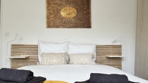 A neatly made bed with a white duvet, two pillows, and a decorative wall piece above it. - DEGEMER MAT! Cosy, Modern, 8 minutes from the beach (Moëlan-sur-Mer)