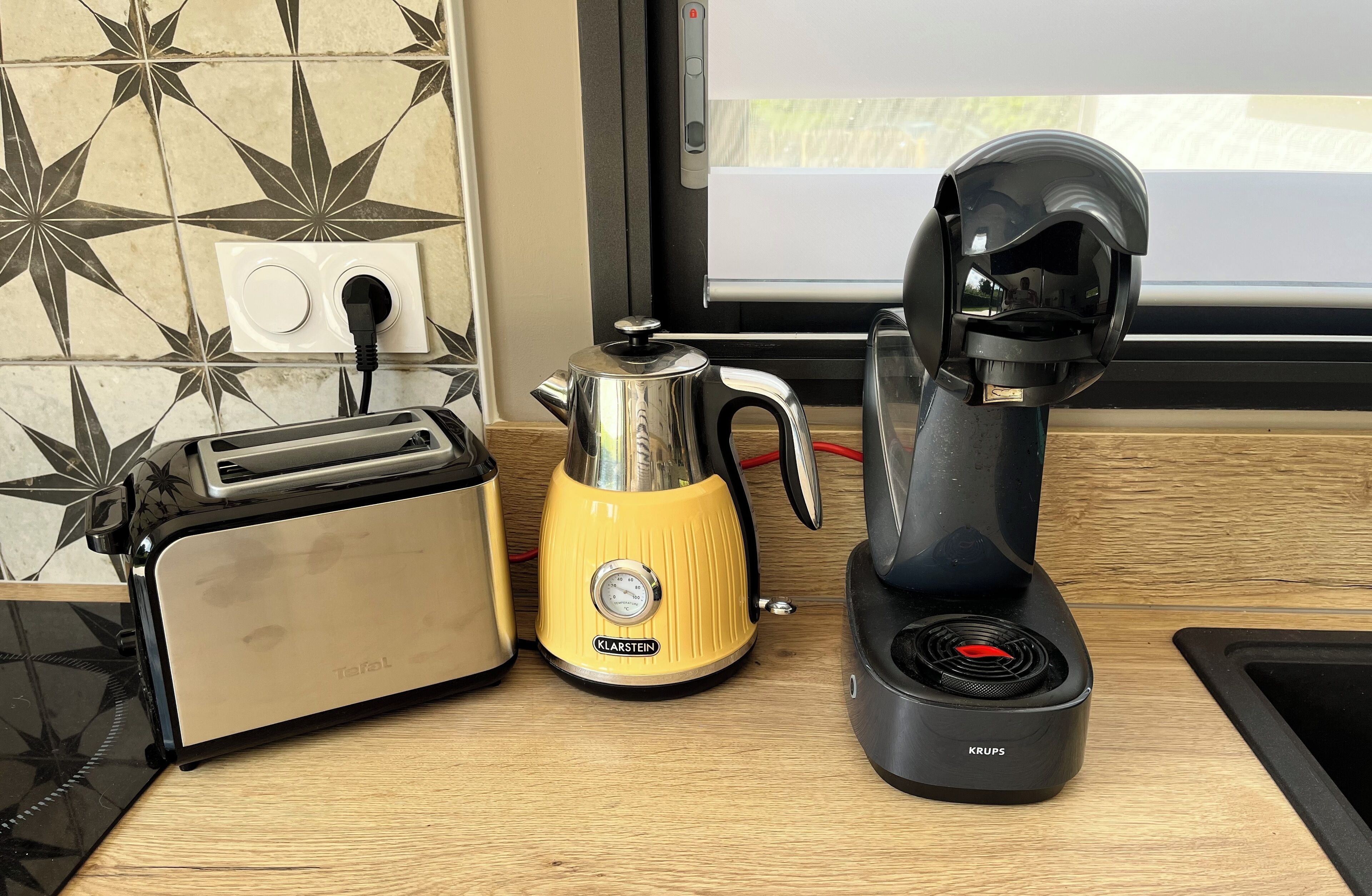 A kitchen counter with a toaster, a yellow Klarstein electric kettle, and a Krups electric coffee maker.