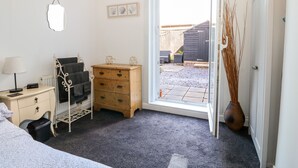 Un dormitorio con cama, cómoda, mesita de noche, ventana con vistas al exterior y puerta que da al exterior.