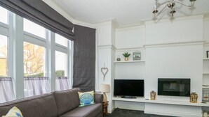 Una sala de estar con un sofá, un televisor de pantalla plana, una lámpara y una chimenea.