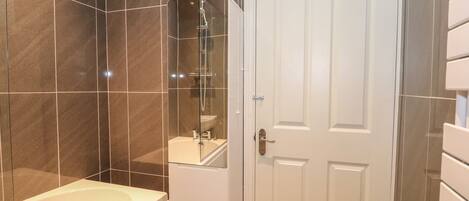 A bathroom with a bathtub, a mirror, and a white door.