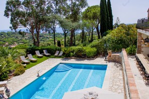 Une piscine entourée de chaises longues, bordée de verdure et offrant une vue imprenable sur un paysage magnifique.