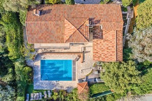 Vue aérienne d’une propriété dotée d’une piscine, d’un patio couvert et d’un mur en pierre.