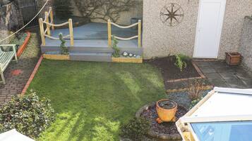 Un pequeño patio trasero con un área de juegos de madera, una planta en maceta y una puerta decorada con una brújula.