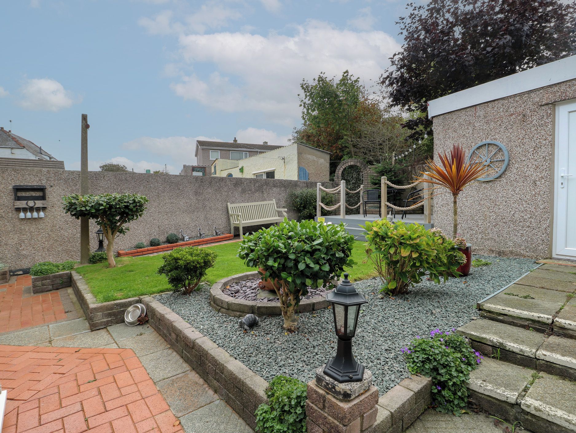 Ein Innenhof mit Bank, Blumentöpfen, einem kleinen Gartenbereich und einer Steinmauer.