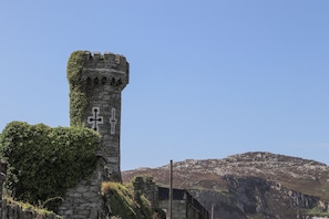 A stone tower with ivy, set against a mountainous backdrop.
