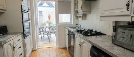 A compact kitchen with a dishwasher, stove, and a view to a patio area.