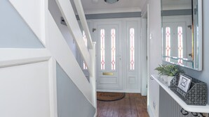 A hallway with white walls, a wooden floor, and a white door with stained glass windows. - Glasfryn (Holyhead)
