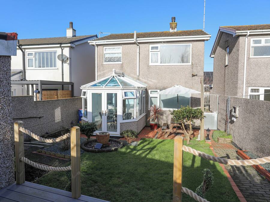 A residential property with a conservatory, a fenced garden, and a paved patio area.