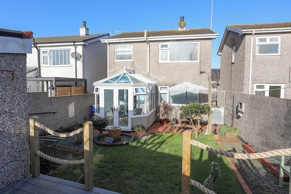 A residential property with a conservatory, a fenced garden, and a paved patio area.