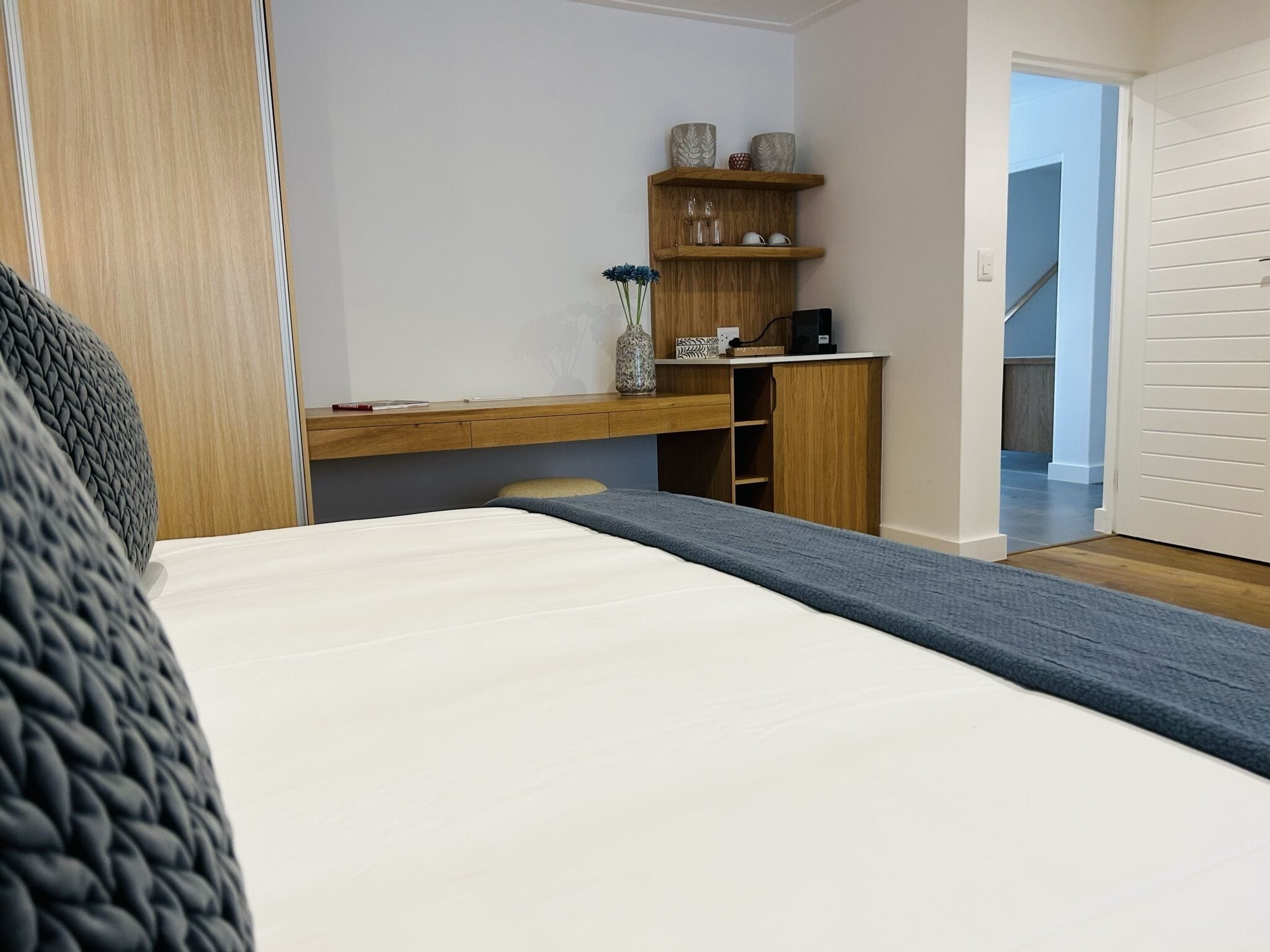 A bedroom with a bed, a desk, and a wardrobe.