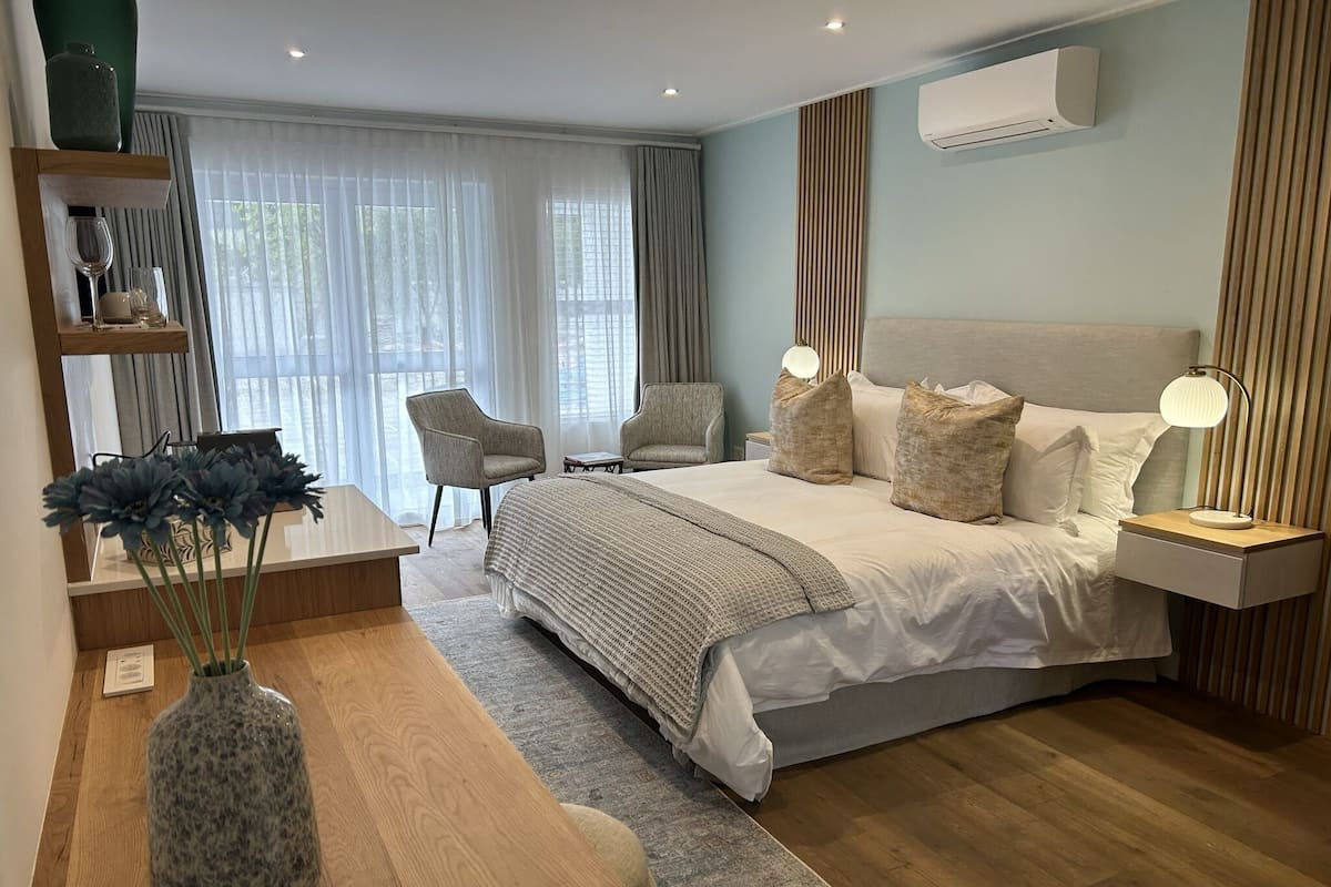 A modern bedroom with a large bed, bedside tables, a desk, and a chair.