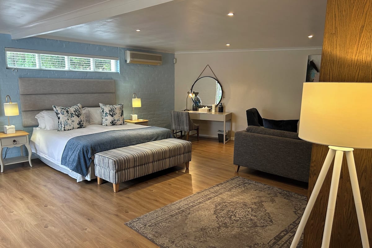 A modern bedroom with a bed, bedside tables, a desk, a chair, and a sofa.