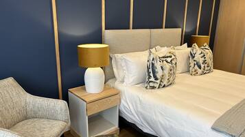 Una habitación de hotel con cama, mesita de noche, lámpara, silla y un libro en el suelo.