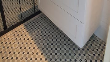 Un baño con un lavamanos blanco, un espejo con marco de madera y un piso estampado.