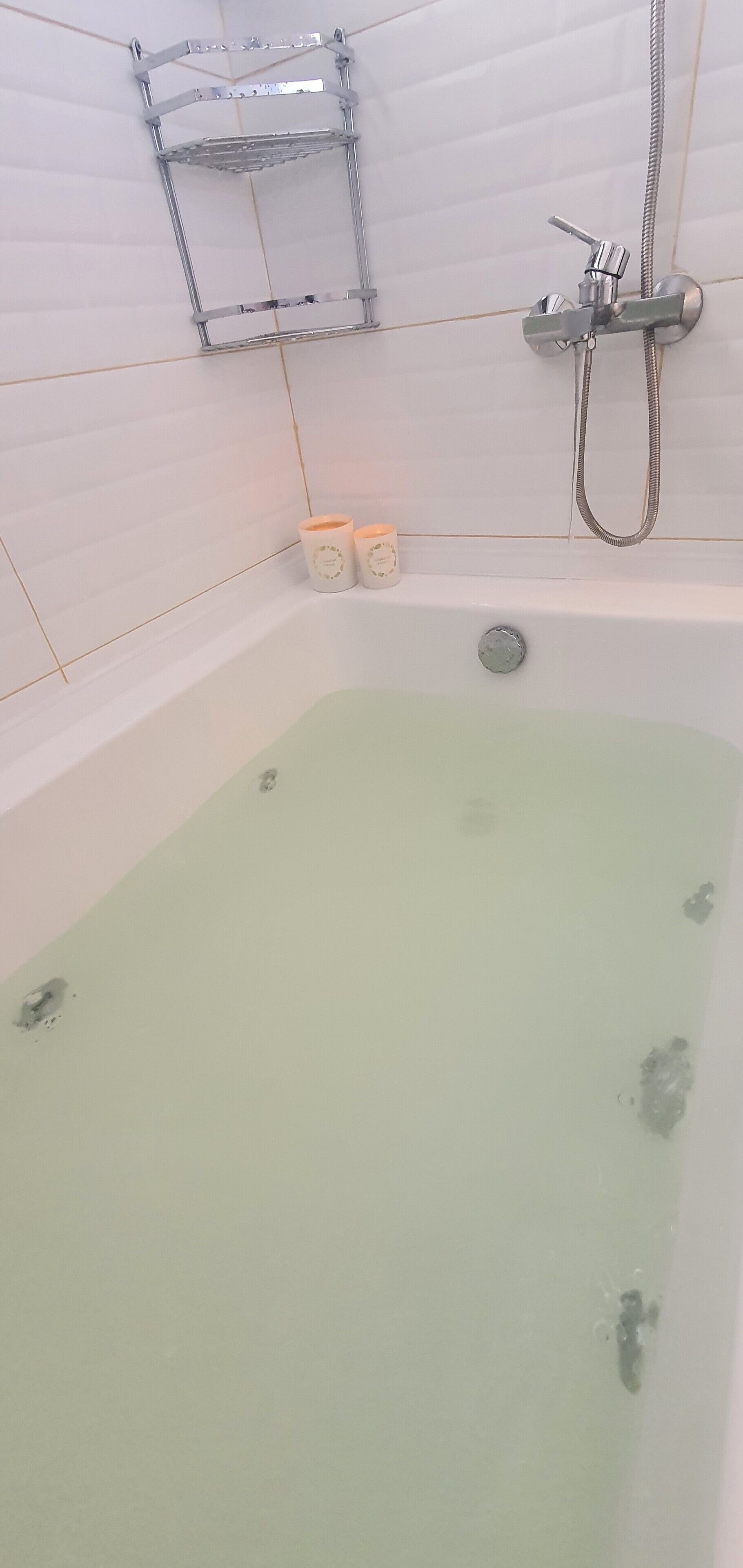 Un baño con bañera, ducha y dos velas en la pared.