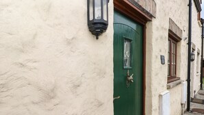 A green door with a small window, a wall-mounted light, and a sign indicating a baby room. - Bwthyn Canol (Haverfordwest)