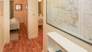 A hotel room with a wooden floor, a bed with a green blanket, a small table, and a large map on the wall. - 2 Chandlers Yard (Burry Port)