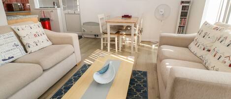 A furnished living room with a sofa, a coffee table, and a dining area with chairs and a table.