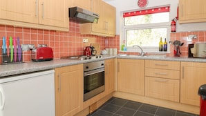 Une cuisine avec des meubles de rangement en bois, un grille-pain rouge, une cuisinière et un évier.