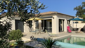 A modern house with a swimming pool, outdoor seating, and a patio area.