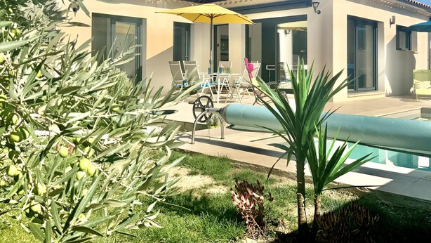 A modern house with a swimming pool, outdoor seating, and a pergola.