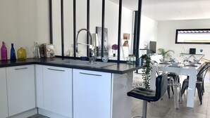 A modern kitchen with white cabinets, a black countertop, and a bar stool.