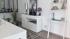 A modern living room with a white entertainment unit, a large mirror, and a bookshelf with books and decorative items.
