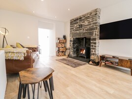 A living room with a stone fireplace, a sofa, a coffee table, and a TV mounted on the wall.