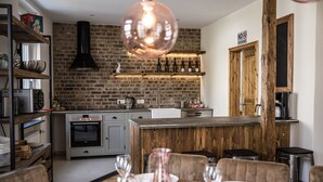 A modern kitchen with a brick wall, wooden shelves, and a dining area with a wooden table and chairs. - Rheinfreunde Bingen das Ferienhaus für Viele (Bingen am Rhein)
