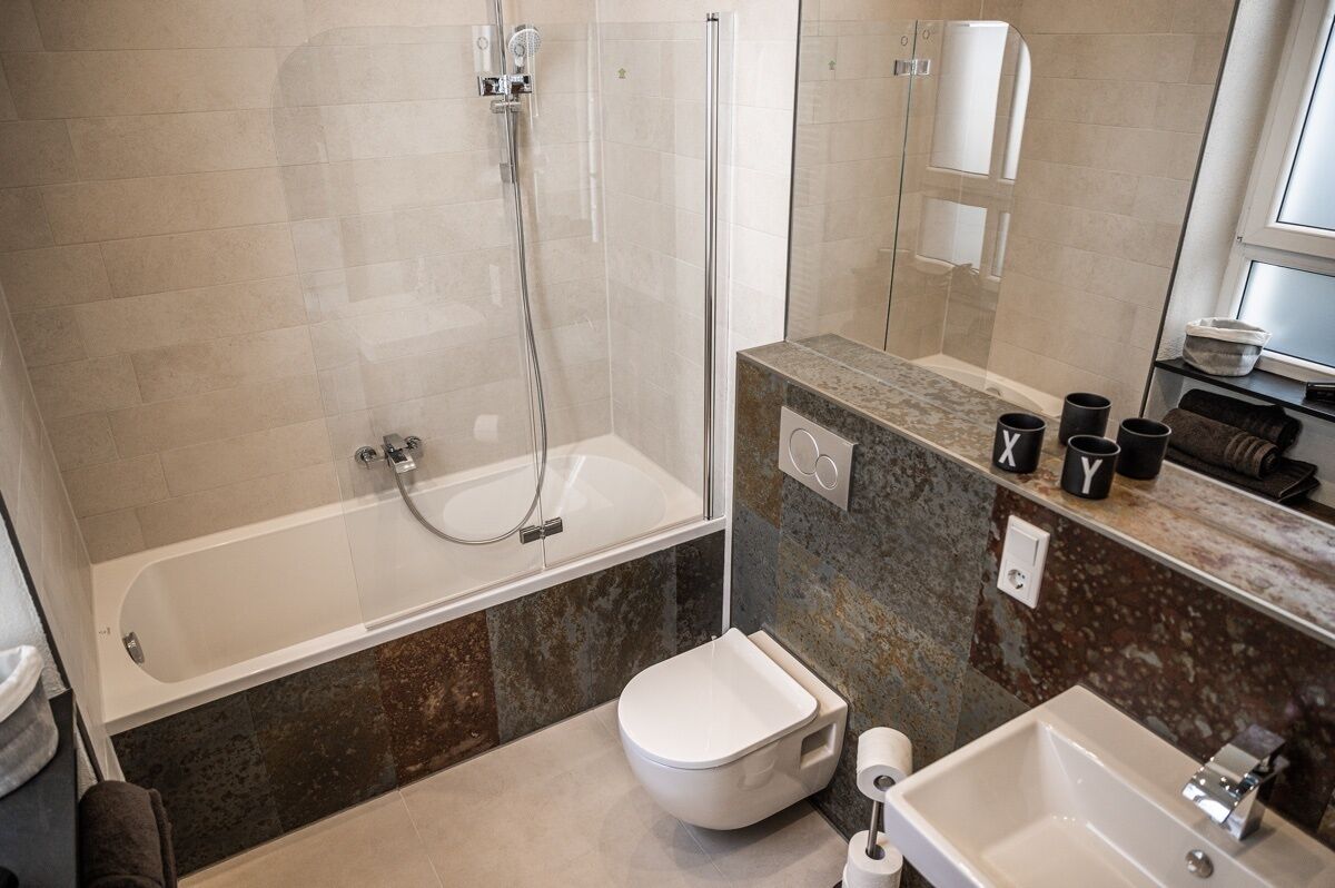 A modern bathroom with a glass-enclosed shower, a standalone toilet, and a sink.