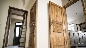 A hallway with wooden doors leading to different rooms, a staircase, and a kitchen area with cabinets. - Rheinfreunde Bingen das Ferienhaus für Viele (Bingen am Rhein)