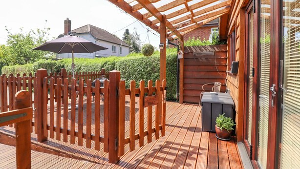 A wooden deck with a pergola, a barbecue grill, and a potted plant. - Varley Villa (Newtown)