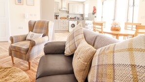 A modern living room with a sofa, armchairs, and a dining table. - Varley Villa (Newtown)