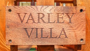 A wooden sign with the text "VARLEY VILLA" mounted on a wooden structure. - Varley Villa (Newtown)