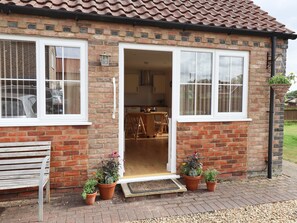 A brick house with a tiled roof, a bench, and potted plants at the entrance. - Copse View (Lincoln)