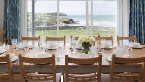 A dining table set for six with a view of the ocean and hills. - The White House (Wadebridge)