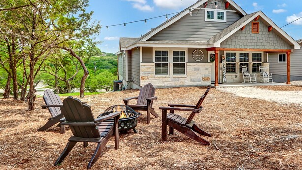Une maison dotée d’un porche abrité, d’un espace extérieur aménagé avec des fauteuils Adirondack et d’un foyer.