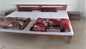 A bed with a wooden headboard, two pillows, and a patterned blanket.