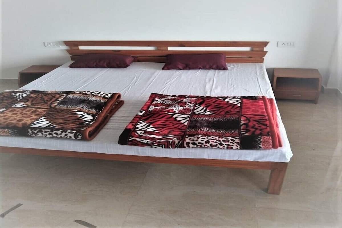 Un lit avec une tête de lit en bois, deux oreillers et une couverture à motifs.