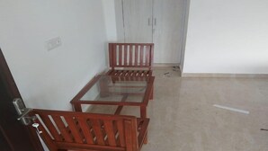 A room with a glass-top dining table and two wooden chairs.