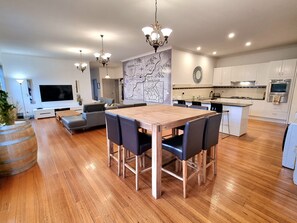 A modern kitchen with white cabinets, a central island, and a dining area with a wooden table and chairs.