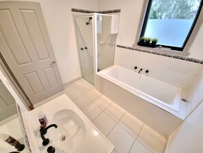 A modern bathroom with a bathtub, shower, and sink.
