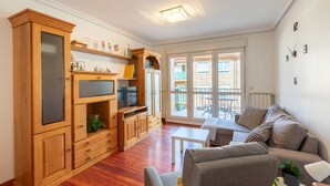 A living room with wooden cabinets, a sofa, a coffee table, and a balcony with outdoor furniture.