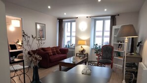 A modern living room with a sofa, coffee table, and a dining area. - La Dolce Vitae (Rodez)