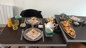 A breakfast setup with plates, cups, and pastries on a table. - La Dolce Vitae (Rodez)