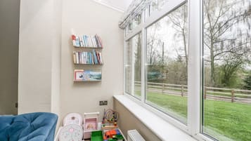 Un cuarto de juegos infantil con un gran ventanal, una estantería y un camión de juguete.