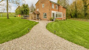 A two-story brick house with a gravel driveway leading to a wooden gate. - Orchard House (Leominster)